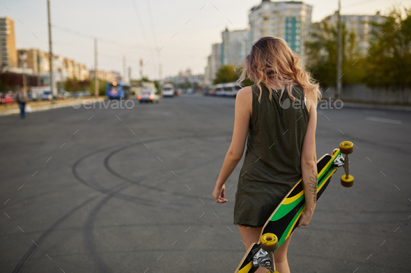 Beautiful young tattooed girl with longboard in sunny weather - Stock Photo - Images