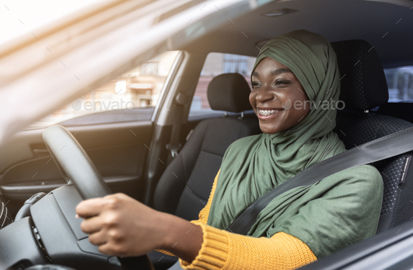 Happy Black Muslim Woman In Hijab Driving Car With Fasten Seat Belt