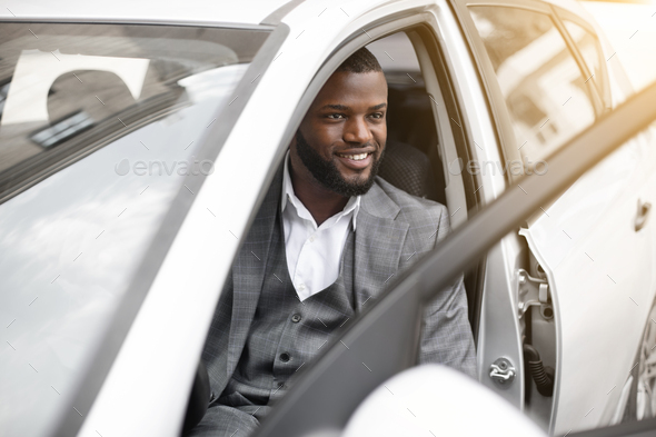 Handsome black businessman in expensive suit getting in car - Stock Photo - Images