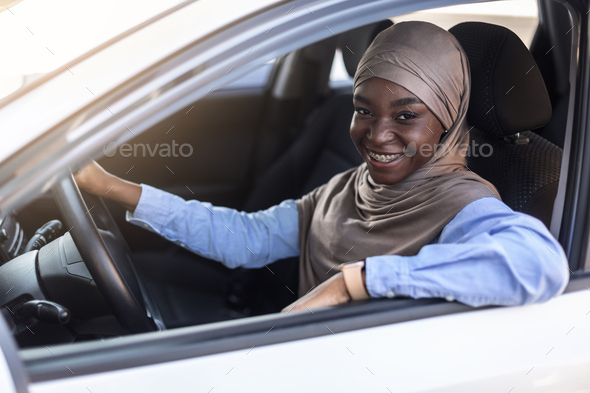 Portrait of happy young black confident muslim woman posing in her car