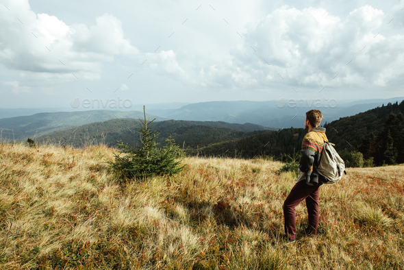 stylish beautiful traveling man hiking in the mountains on a background of a forest - Stock Photo - Images