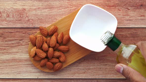 Almond Nut and Oil Pouring in a Container on Table alt