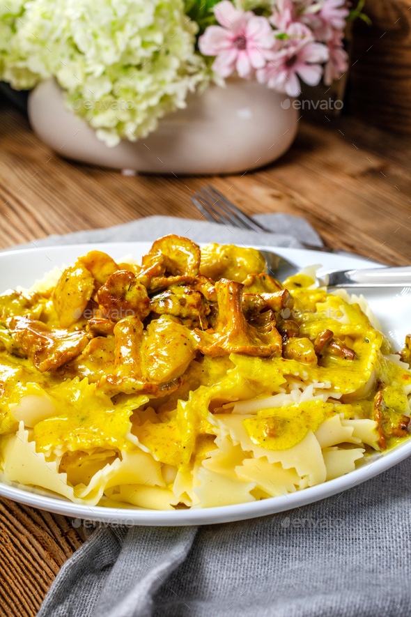Pasta with fried chicken in cream and chanterelle sauce. Stock Photo by