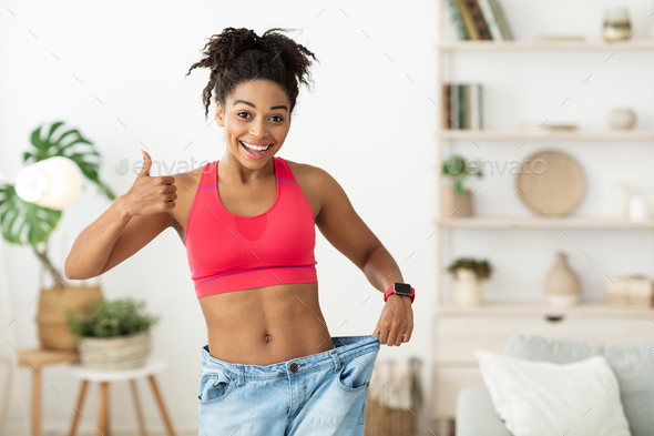 African Woman Showing Weight Loss Result Wearing Oversize Jeans Indoor