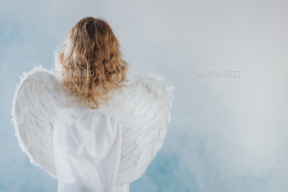 Little angel with wings standing in heaven