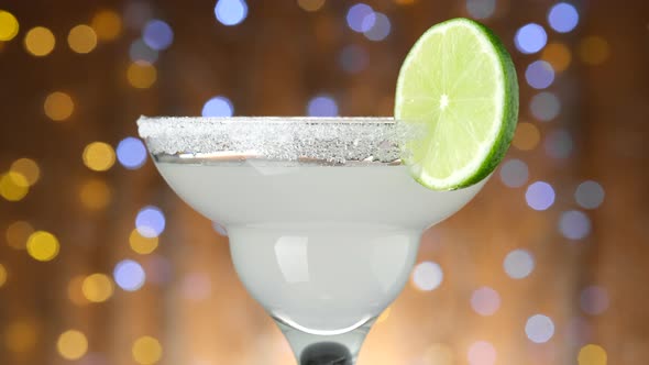 Classic Margarita cocktail over Blinking boken Background, rotate. alt