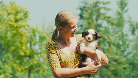 Portrait of an Adult Woman with a Puppy Wet Together in the Summer Rain alt