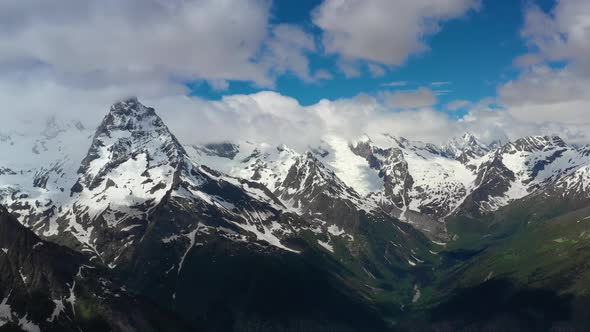 Air Flight Through Mountain Clouds Over Beautiful Snowcapped Peaks of Mountains and Glaciers alt