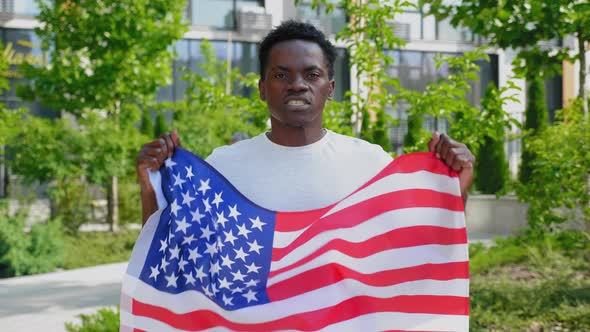 Portrait Afroamerican Man Holding an American Flag Looks Camera and Says USA alt