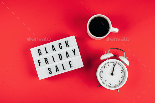 Black friday sale word on lightbox, cup of coffee, alarm on red background table. Flat lay - Stock Photo - Images