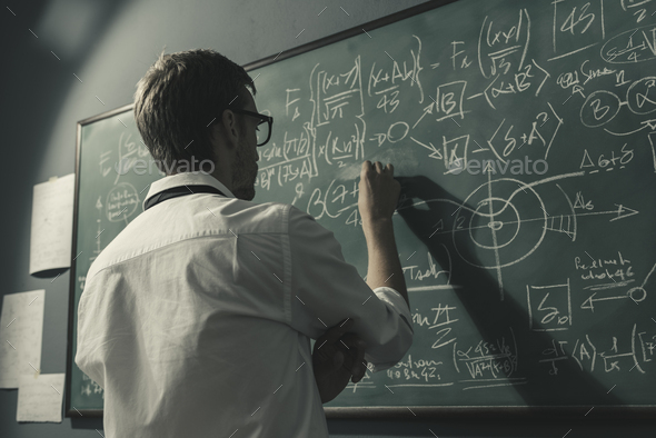 Young smart mathematician drawing on the chalkboard - Stock Photo - Images