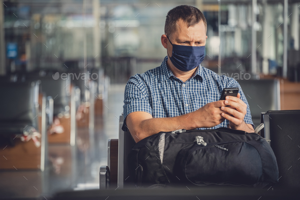Man with a mask talking on mobile phone in airport lounge - Stock Photo - Images