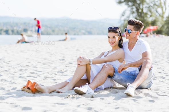 Romantic young couple sitting at a beach - Stock Photo - Images