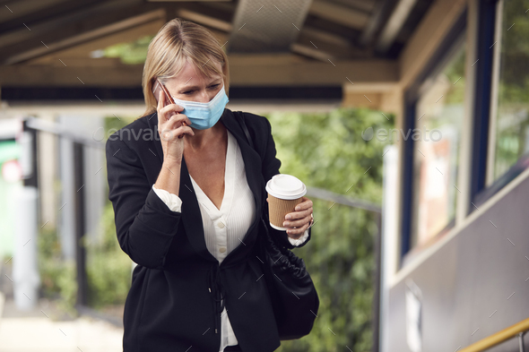 Businesswoman At Railway Station Talks On Mobile Phone Wearing PPE Face Mask During Health Pandemic