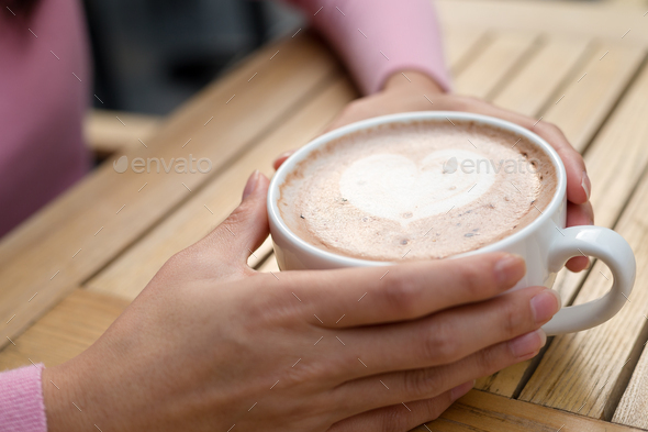 Woman holding hot coffee at outdoor cafe - Stock Photo - Images