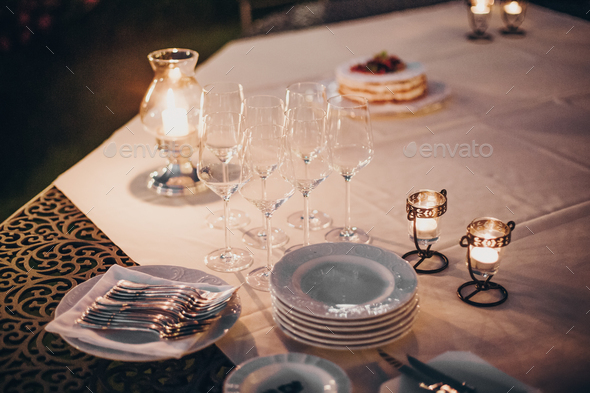 Wedding table with candles, cutlery and plates, champagne drink and glasses