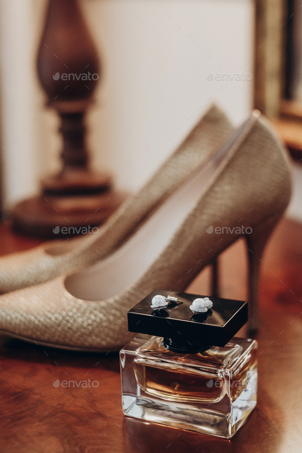 luxury wedding morning preparation with bride shoes perfume and expensive earrings in hotel room. golden details for stylish modern bride. wedding boudoir moment. space for text.