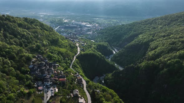 Flight above road through idyllic Italian village in alp valley hillside; drone alt