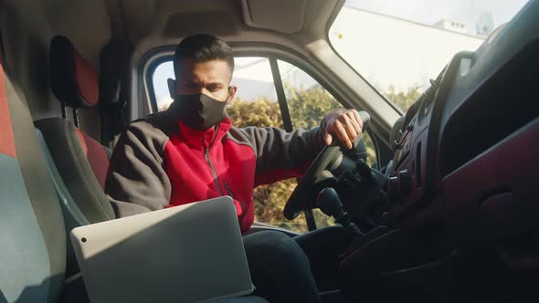 Young Man Looking at the Laptop and Starting the Engine of the Van alt