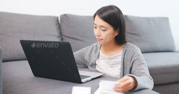 Woman using laptop computer for recording the expense of the receipt
