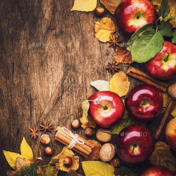 Autumn food background. Ripe apples with nuts, fallen leaves and cinnamon on rustic wooden table. Top view. Copy space