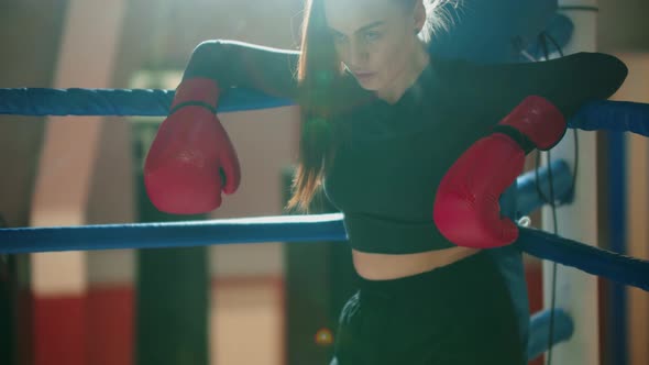 An Attractive Young Woman with Long Hair Resting on the Boxing Ring alt