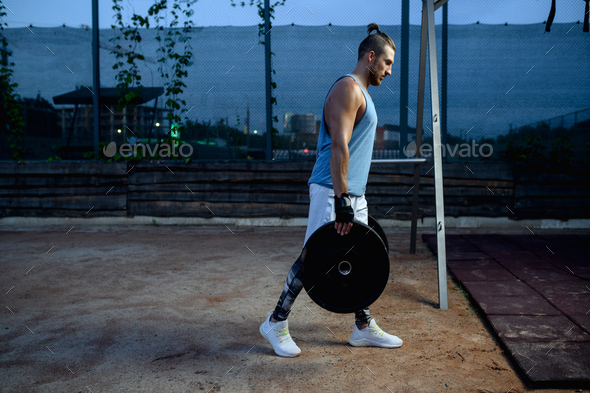 Man carries barbell weights, street workout - Stock Photo - Images