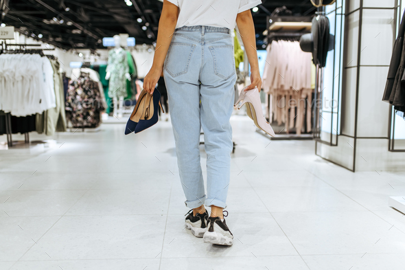 Young woman holds many shoes in clothing store - Stock Photo - Images