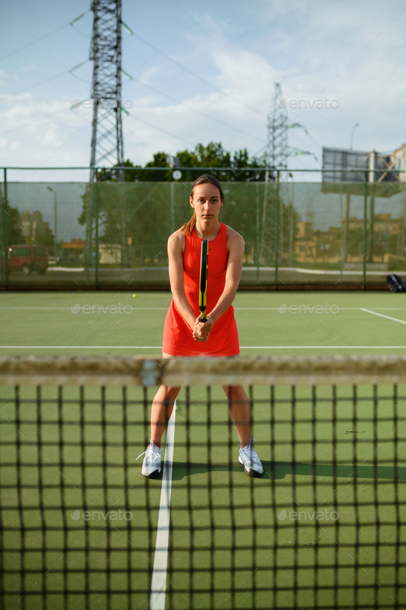 Female tennis player with racket at the net on outdoor court. Active healthy lifestyle, sport game competition, fitness training with racquet