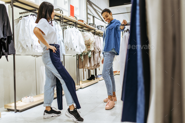 Two girls trying on clothes in clothing store Stock Photo by