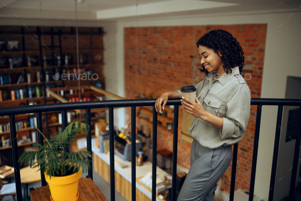 Female student with cup of coffee standing in cafe - Stock Photo - Images