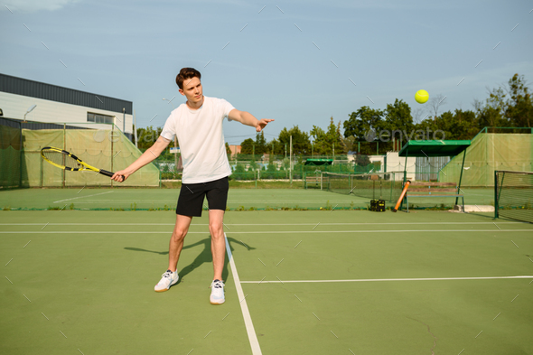 Male tennis player with racket hits the ball - Stock Photo - Images