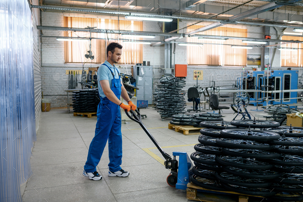 Worker carries bicycle wheels on a cart, factory - Stock Photo - Images