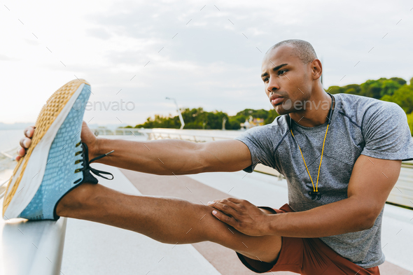 Confident young african sports man stretching Stock Photo by