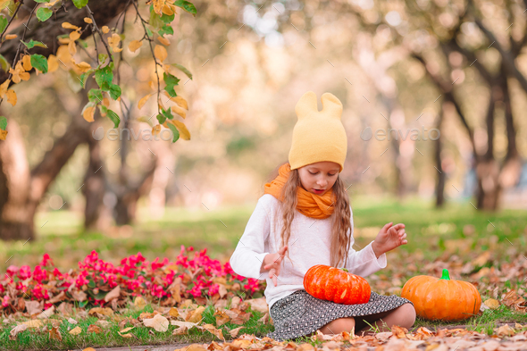 Little adorable girl with pumpkin outdoors on a warm autumn day - Stock Photo - Images
