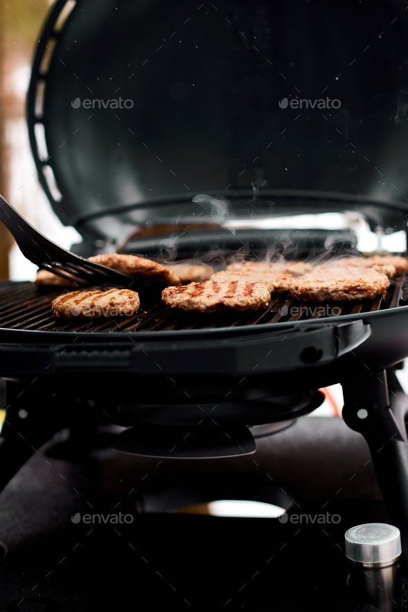 Man grilling steaks on a portable BBQ, Snowy winter barbecue - Stock Photo - Images