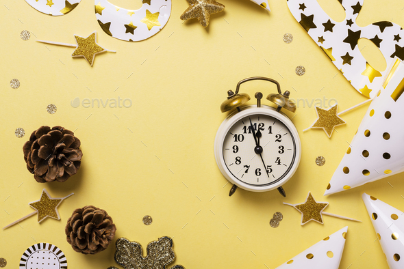 Christmas card with party hats, masks and clock on the yellow background. Top down view with copy space
