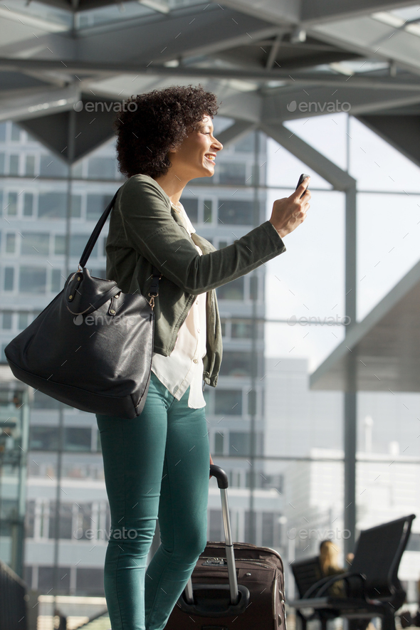 happy african American travel woman at station with mobile phone and luggage - Stock Photo - Images
