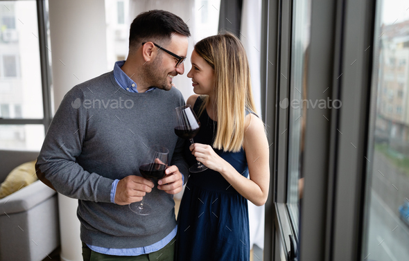 Cheerful beautiful young couple hugging and drinking red wine at home - Stock Photo - Images