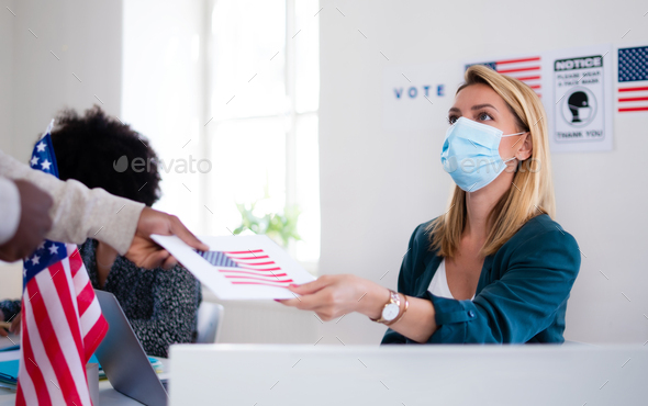 People with face mask voting in polling place, usa elections and coronavirus