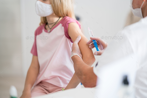 Midsection of child with face mask getting vaccinated, coronavirus, covid-19 and vaccination concept - Stock Photo - Images