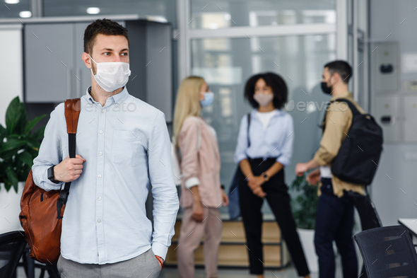 New normal and returning to work after epidemic. Young guy with backpack in protective mask looks to