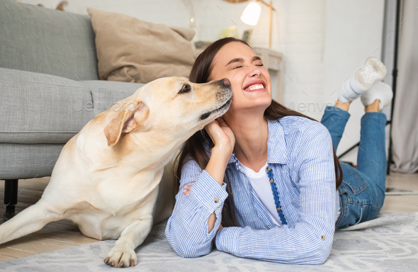 Young smiling woman with dog lying on floor - Stock Photo - Images