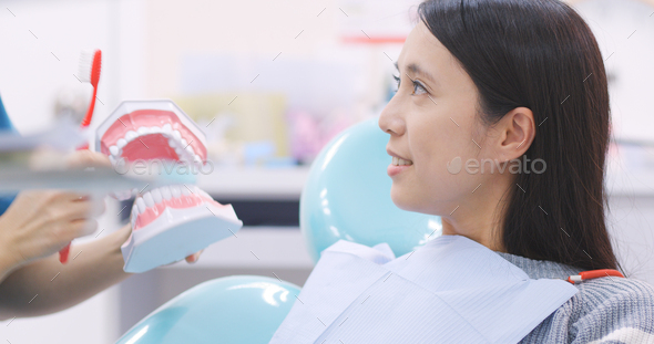 Dentist showing patient how to brush teeth in dental clinic - Stock Photo - Images