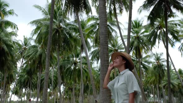 Slow motion of a young woman with hat looking at coconut trees in the garden