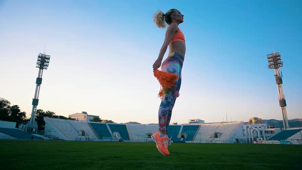 Beautiful young gymnast in bright clothes makes a pirouette at the stadium alt