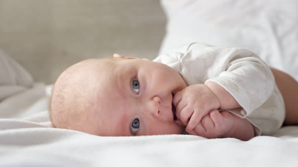 Little Baby Girl Lies on Belly on Parent Bed alt