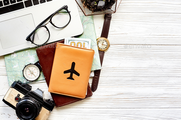 travel and wanderlust concept, planning summer vacation background flat lay, space for text. map compass photo camera glasses wallet watch laptop on white wooden table top view