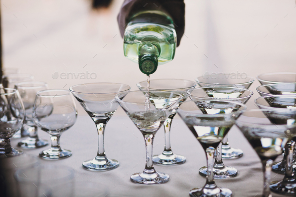 Waiter pouring martini in crystal glasses on table party at wedding reception