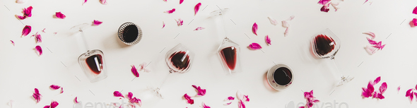 Glasses with red wine and pink flowers, wide composition - Stock Photo - Images